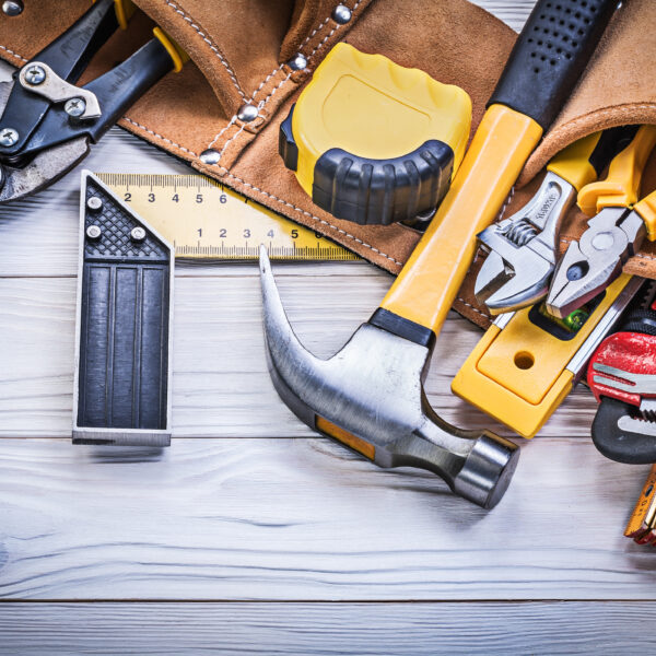 Leather tool belt with construction tooling on wooden board maintenance concept.